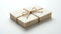 Stack of aged paper sheets tied with natural twine bow on white background, suitable for packaging, stationery, craft projects, and vintage design concepts.