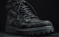 Black lace-up work boot with chunky tread sole and textured suede upper, isolated on dark background for footwear design and retail use.