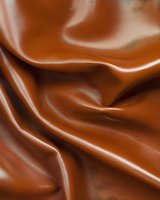 Smooth flowing milk chocolate background with silky waves and creamy texture creates luxurious abstract pattern for confectionery and dessert designs.