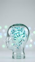 Transparent glass head filled with blue and white medical capsules pills on bokeh background representing pharmaceutical medicine and brain health.