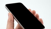 Close-up of hand holding smartphone with blank black screen on white background, isolated for app mockup and digital marketing design use.