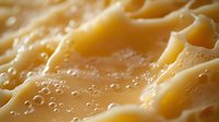 Creamy melted cheese texture with tiny air bubbles in golden yellow color, extreme macro close up showing rich dairy food surface details.