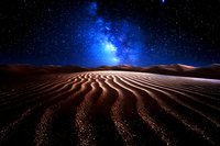 Majestic desert sand dunes under bright blue night sky with stars and milky way galaxy, dramatic rippled sandy landscape illuminated by moonlight creating patterns.