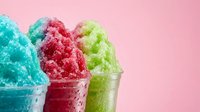 Colorful shaved ice cups in turquoise, red, and lime green flavors against pink background. Use for summer beverage, frozen dessert, and refreshment marketing materials.
