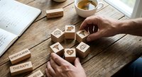 Mental health therapy concept with wooden blocks featuring wellness symbols on rustic desk. Professional counseling and psychological support tools.