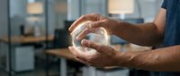Male hands holding glowing crystal ball in modern office environment, symbolizing future vision, business strategy, innovation and corporate planning concepts.