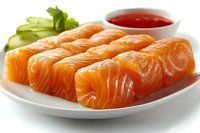 Fresh raw salmon sashimi slices served on white plate with cucumber garnish and red dipping sauce, showcasing vibrant orange color and marbled texture.