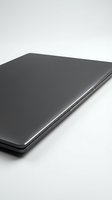 Closed slim dark gray laptop on white background, side view showing thin profile and metal finish, isolated for tech and business use.