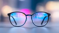 Round eyeglasses reflecting digital code matrix on lenses against blurred city lights background, representing modern technology and artificial intelligence concept.