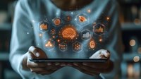 Digital hologram with artificial intelligence brain and technology icons floating above tablet device in hands against dark background with bokeh effect.