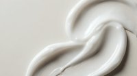 Smooth white cream texture with flowing curves creating elegant swirls on neutral background for skincare and cosmetic product applications.