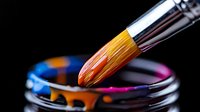 Paint brush dipping into vibrant acrylic colors in glass jar, macro shot showing bristle detail against dark background, artistic supplies for creative projects.