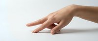 Caucasian woman's hand with manicured nails resting on white surface, suitable for beauty, skincare, wellness, and cosmetic product advertising campaigns.
