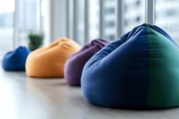 Colorful bean bag chairs lined up in modern office space with natural lighting, creating comfortable casual seating area for relaxation and collaboration.