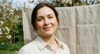 Young Caucasian woman smiling outdoors near clothesline with natural linen fabric, sustainable lifestyle and eco-friendly living concept for marketing.
