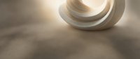 Modern abstract ceramic sculpture with curved flowing forms casting soft shadows on neutral surface with warm lighting for contemporary interior design.