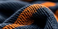 Close-up macro shot of woven fabric texture in navy blue and orange colors showing detailed pattern of textile weave structure with selective focus and blur effect.