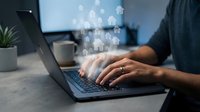 Professional working on laptop with digital human resources icons floating above keyboard representing online recruitment and HR management technology.