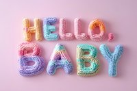 Colorful knitted letters spelling Hello Baby in pastel rainbow colors on pink background, perfect for baby shower invitations and nursery decorations.