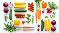 Fresh organic vegetables and herbs arranged on white background including tomatoes, carrots, peppers, onions, zucchini, radishes and leafy greens for healthy cooking.