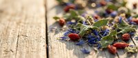 Colorful dried herbs and flower petals scattered on rustic wooden surface for natural wellness, aromatherapy, tea blending and organic cooking applications.