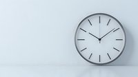 Minimalist wall clock with silver frame against white wall showing nearly eleven o'clock, representing time management and modern interior design style.