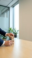 Businessman hands stacking wooden blocks with eco-friendly icons on office desk. Sustainable business development and environmental responsibility concept.