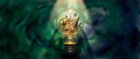 Glowing light bulb with gears inside surrounded by swirling green and blue energy representing innovation, creativity and mechanical engineering concepts.