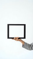 Hand holding black empty picture frame against white background for mockup and presentation design.