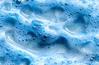 Macro shot of soap foam texture with blue water bubbles and abstract liquid patterns creating dynamic surface with light and shadows.