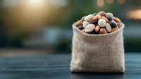 Mixed nuts and dried fruits in rustic burlap sack on wooden table with soft bokeh background, healthy snack concept for natural food packaging design.