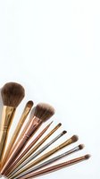 Professional makeup brushes set with gold and rose gold handles arranged in fan pattern on white background for beauty and cosmetics applications.