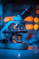 Laboratory microscope with blue and orange lighting against blurred bokeh background, suitable for science, medical research, education, and healthcare presentations.