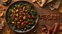 Autumn vegan kale salad with roasted sweet potato, cranberries, and pecans on rustic wooden table with fall leaves and pecan lettering.