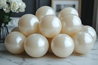 Pearly white balloons arranged in pyramid formation on marble surface, with soft natural lighting creating gentle highlights and reflections. White roses in background.