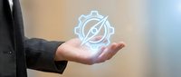 Businessman hand holding glowing compass icon with gear symbol, representing navigation, direction, strategy, and business solutions for corporate guidance.