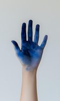 Hand with blue paint gradient fading from fingertips to wrist on neutral background for creative design projects and artistic concepts.