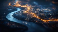 Aerial night cityscape with winding river and glowing streets creating luminous pattern, tilt-shift effect adds dreamy miniature look. Moody dark blue atmosphere.