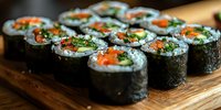 Fresh sushi rolls with salmon, cucumber, and avocado wrapped in nori seaweed on wooden serving board, close-up view showing vibrant ingredients and texture.