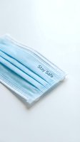 Blue disposable protective face mask with Stay Safe text on white background, symbolizing health awareness and virus prevention.