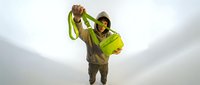 Male construction worker in safety gear holding measuring tape above head on white background, ready for design use.