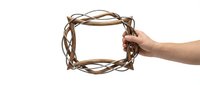 Hand holding rustic woven twig frame border isolated on white background for natural organic design projects and craft decorations.