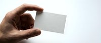 Male hand holding blank white business card mockup against clean background for branding and corporate identity design projects.