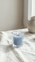 Blue scented candle burning in glass holder on marble surface creating cozy atmosphere for relaxation and home decor in bright interior space.