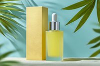 Yellow serum bottle with dropper and packaging on turquoise background with tropical palm leaves, for skincare product advertising.