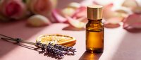 Amber essential oil bottle with dried lavender flowers and orange slices on pink surface. Natural aromatherapy spa wellness beauty treatment skincare concept.