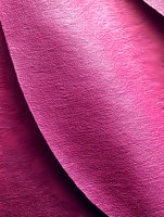 Pink textured fabric with diagonal fold creating subtle shadow and light interplay, showcasing luxurious material surface with fine woven detail and depth.