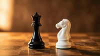 Black king and white knight chess pieces on wooden board with warm lighting creating strategic business concept for competition and planning.