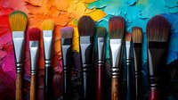 Paint brushes arranged in row against vibrant multicolored oil paint texture background showing artistic tools and creative painting supplies for fine art and craft projects.