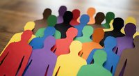 Colorful paper cutout figures representing diversity, teamwork and community standing together on wooden surface for social concepts.